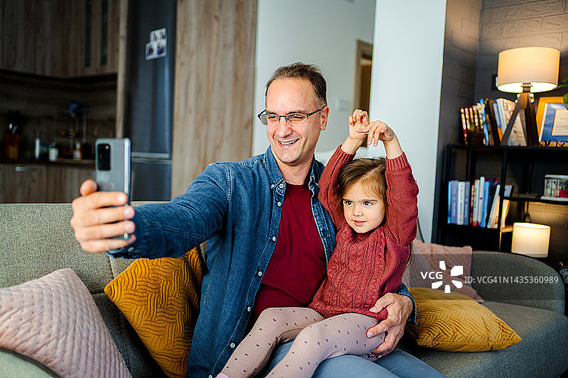 单身父亲和可爱的女儿在客厅自拍图片素材