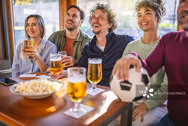 世界杯期间，快乐的体育迷在酒吧里看电视上的足球比赛。图片素材