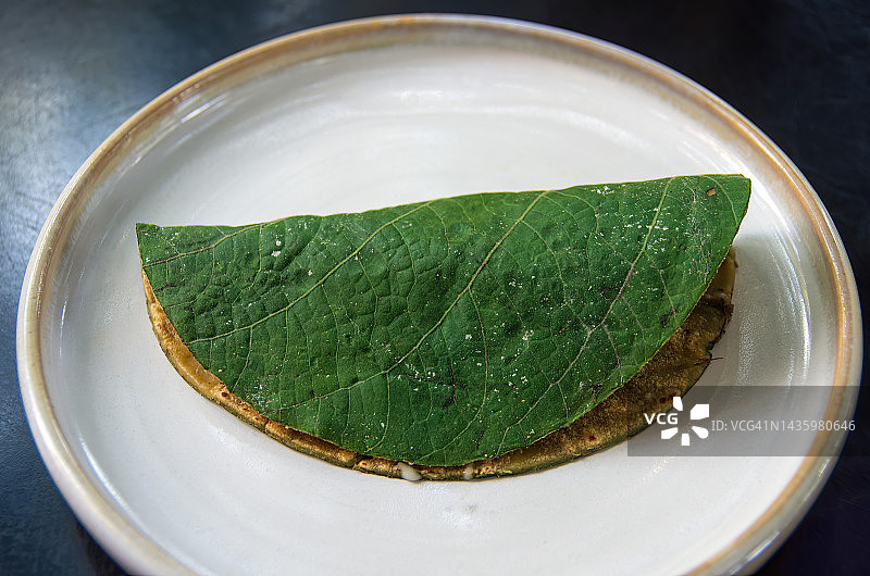 墨西哥玉米卷(牛油果玉米卷配圣叶/圣叶[Piper auritum]裹玉米饼)放在盘子里图片素材