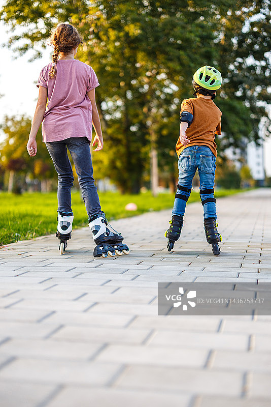 在阳光充足的公园里，孩子们穿着溜冰鞋的后视图图片素材