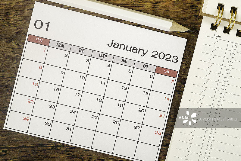2023日历桌:一月是组织者在木制背景下用白色铅笔和清单纸做计划和截止日期的月份。图片素材