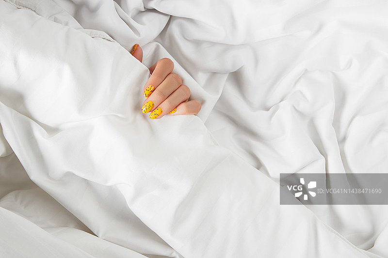 修剪整齐的女人在床上用时髦的指甲设计。美容图片素材