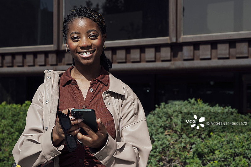 现代非裔美国妇女在户外使用智能手机的肖像图片素材