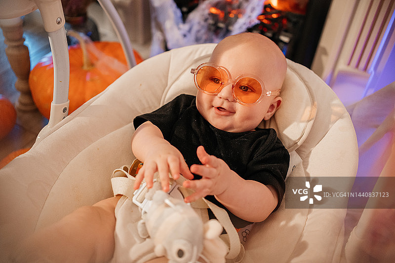 戴眼镜的婴儿在一个舒适的房子里玩电子秋千图片素材