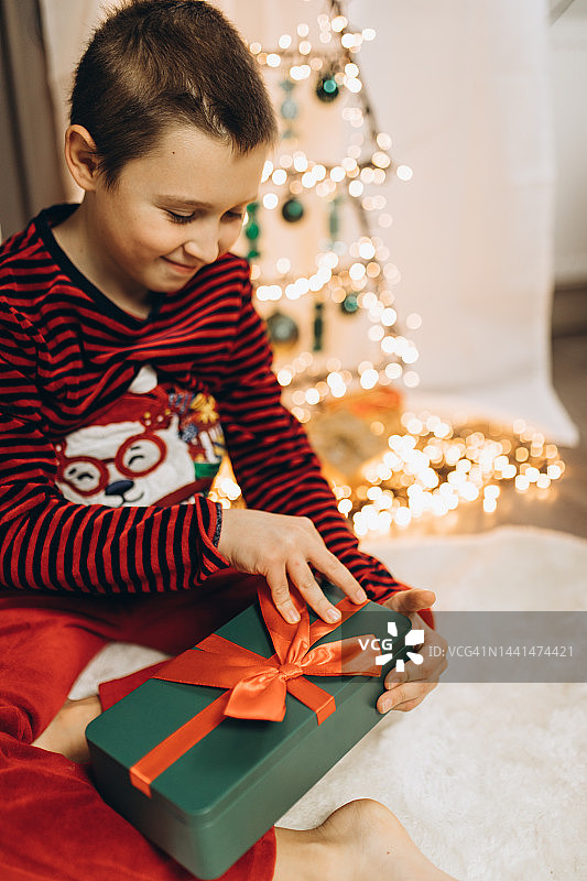 快乐的男孩打开圣诞礼物。图片素材