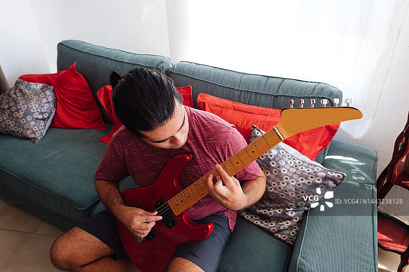 男人在家里的沙发上弹吉他图片素材