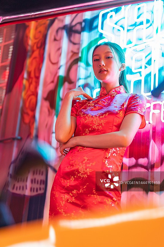 工作室肖像照片的美丽年轻的亚洲女性模特穿着优雅的红色传统中国服装旗袍服装与冷静的情绪看站在一辆嘟嘟出租车车辆旁边图片素材