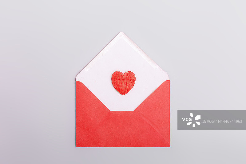 灰色背景下的红包和爱心。情人节的概念，爱情，约会和婚礼。情书的象征。图片素材