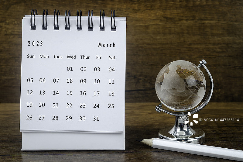 2023日历桌:三月是组织者用水晶球和白色铅笔在木制桌子背景下制定计划和截止日期的月份。图片素材