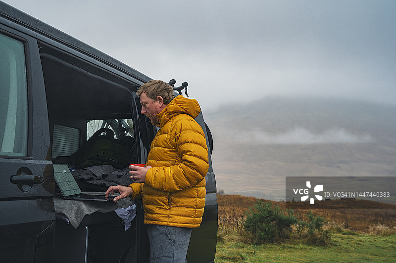 在苏格兰高地，一个成熟的男人在他的露营车里忙着工作图片素材