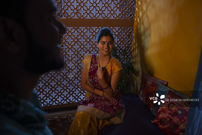 微笑的古吉拉特邦妇女坐在迪万，看着她的丈夫图片素材
