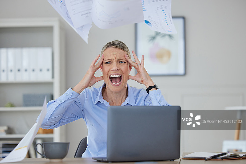愤怒，压力和女人在办公桌上尖叫，因为工作问题的沮丧和恐惧。在公司工作期间，因审计、税务或破产的消息而严重恐慌、愤怒或头痛。图片素材