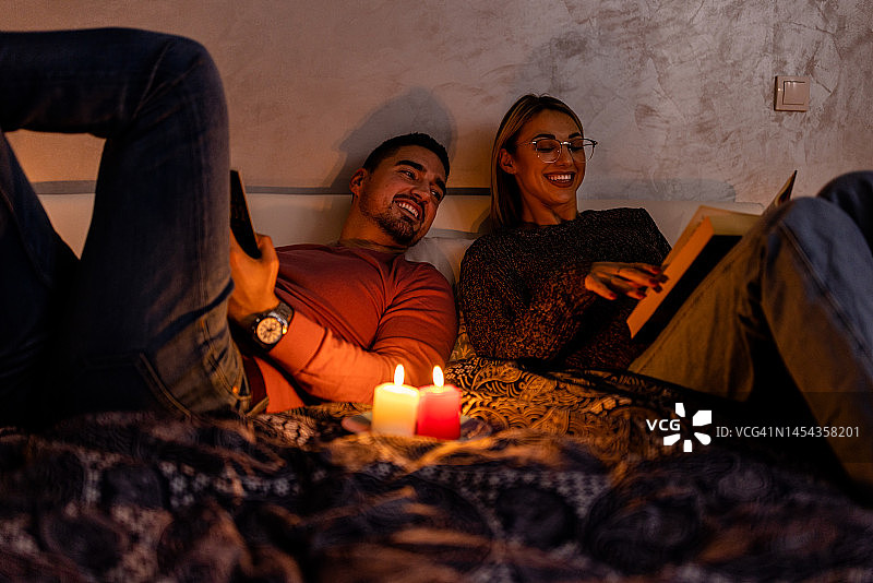 一个男人和他的女朋友躺在一间由电力危机和停电引起的黑暗的房间里。图片素材