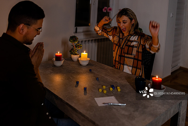 在一次精神危机中，一个男人和一个女人在黑暗中点着蜡烛玩骰子游戏。图片素材