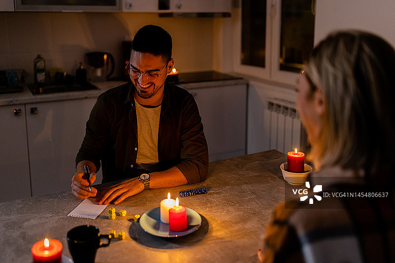 在一次电力危机中，一对年轻男女坐在家里玩骰子游戏。图片素材