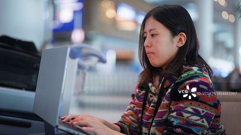女游客在机场等待时使用笔记本电脑图片素材