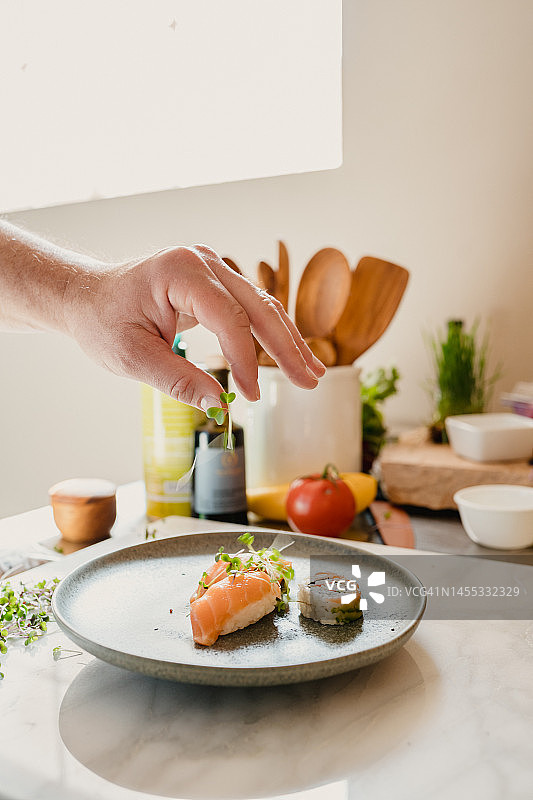 手工添加微绿色蔬菜到寿司盘中图片素材