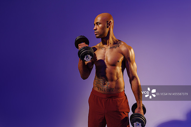 肌肉男子在工作室背景做举重哑铃锻炼。力量和动力图片素材