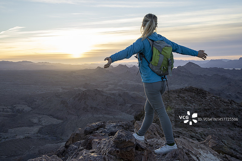 日出时，女徒步旅行者在山脊上放松图片素材