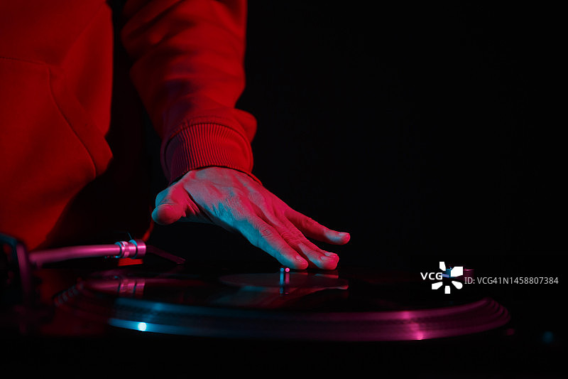 唱片播音员在转盘播放器上刮黑胶唱片。嘻哈DJ在夜总会的派对上播放音乐图片素材