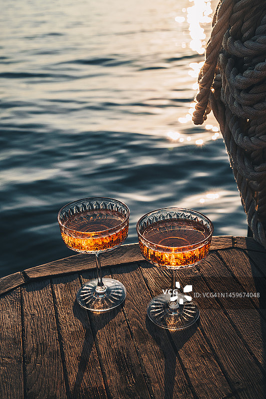 游艇上的奢华约会，日落时分，两杯香槟和起泡的玫瑰葡萄酒图片素材