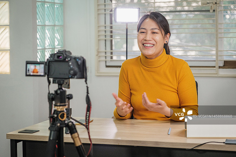 亚洲女性视频博主从她的办公室使用相机教程视频直播到社交网络通过互联网在家里图片素材