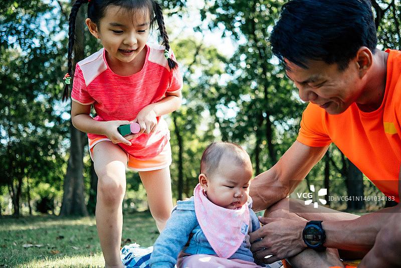 可爱的女婴和一个兄弟姐妹玩野餐与父亲图片素材