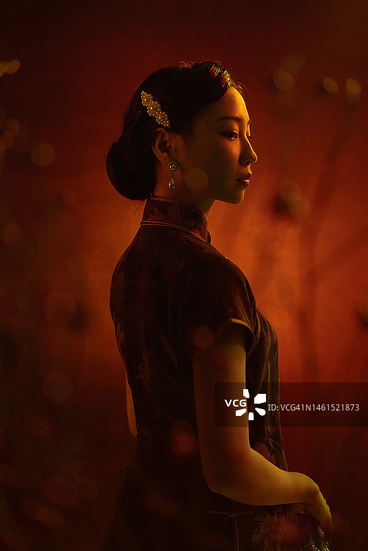 侧面观看美丽的中国女子在旗袍拍摄的工作室肖像设置图片素材