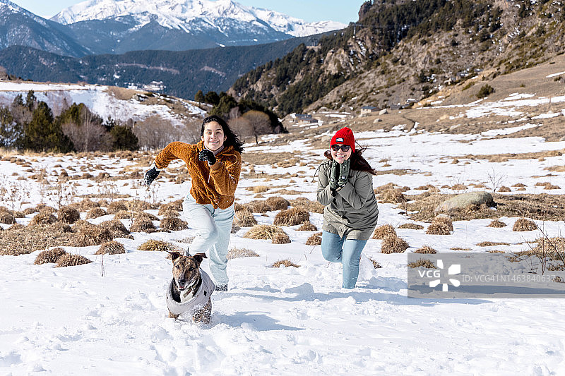 在安道尔比利牛斯山脉，一名拉丁妇女带着狗享受雪天。图片素材