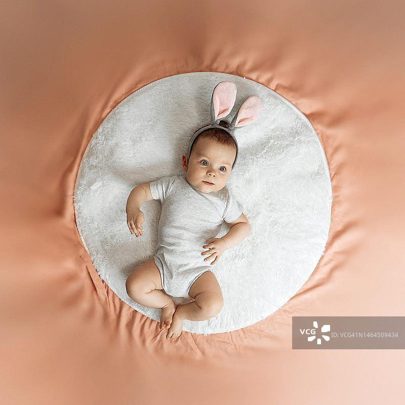 一个惊讶的新生儿躺在床上，戴着兔子耳朵图片素材