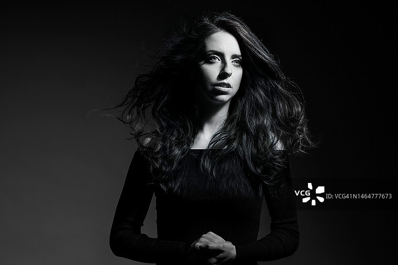 年轻女子的肖像与长发站在黑色背景，意大利图片素材