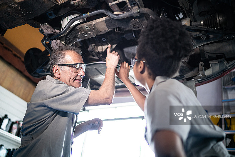 汽车修理工在修理厂教他的助手图片素材