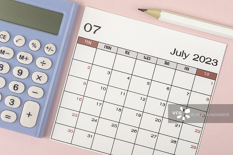 2023日历台:七月是组织者用白色铅笔和计算器在灰色纸张背景下制定计划和截止日期的月份。图片素材