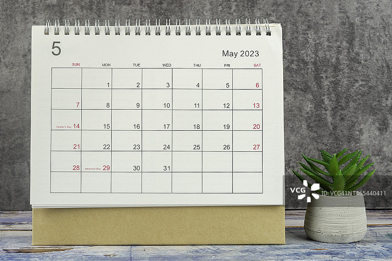 日历桌2023:五月是组织者计划和截止日期的月份，在混凝土墙背景下放置室内植物。图片素材