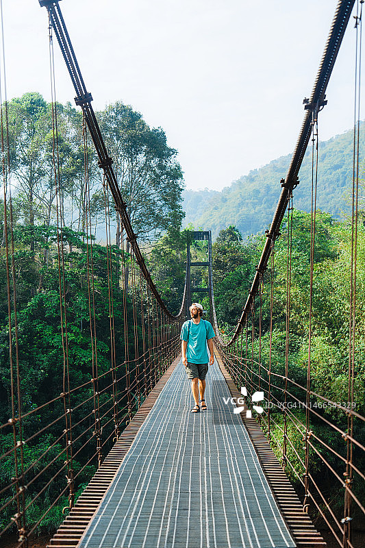 男子走在泰国丛林中的吊桥上图片素材