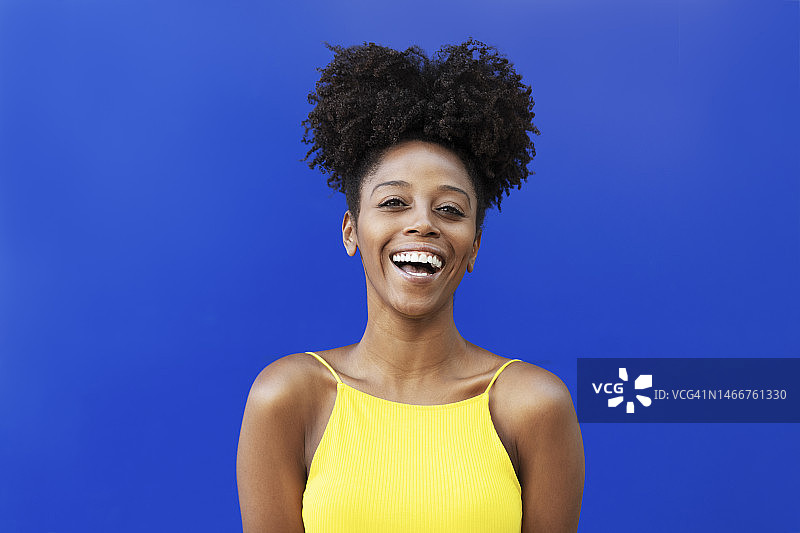 年轻女子与非洲发型笑在蓝色的背景图片素材