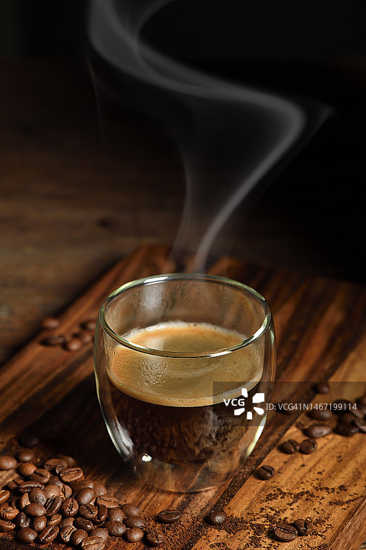 老木头背景上有烟雾和咖啡豆的咖啡杯图片素材
