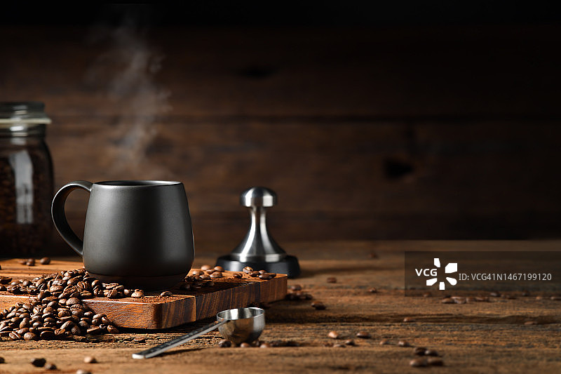 一杯咖啡，烟雾和咖啡豆在旧的木制背景图片素材