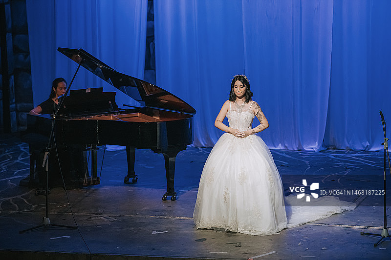年轻的中国戏曲女歌唱家在钢琴师的伴奏下独唱图片素材
