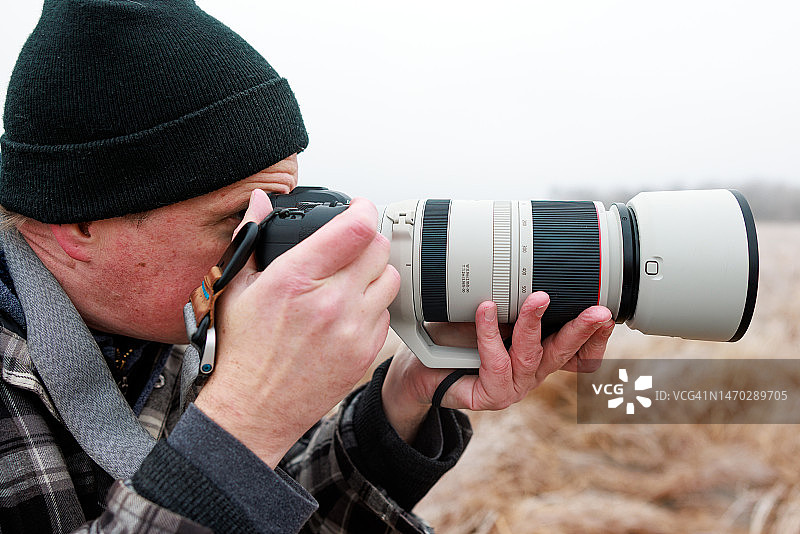 在加拿大安大略省南兰开斯特，一名男子拿着相机对着天空拍照图片素材