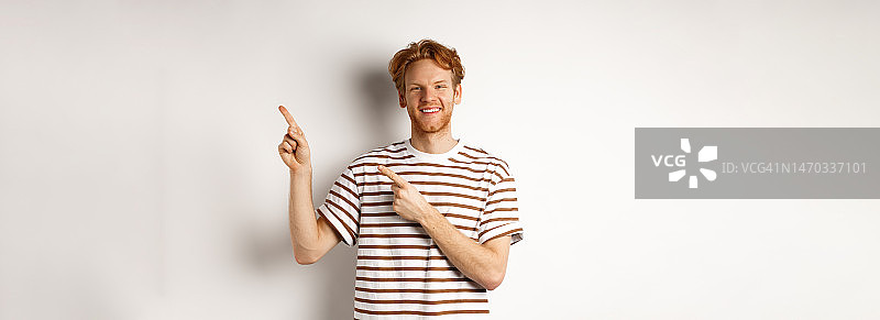 英俊的红发男子显示标志，指着手指对和微笑图片素材