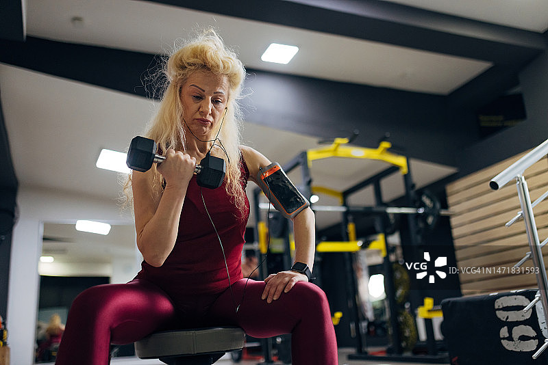 一个积极的生活方式的女人在健身房举哑铃图片素材