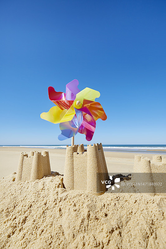 沙滩上有彩色风车的沙堡，衬着大海和蓝天图片素材