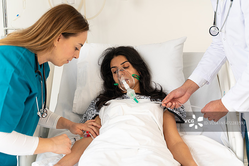 戴着防护口罩的医生正在医院检查感染患者。在医院，病人戴着氧气面罩躺在床上休息。图片素材