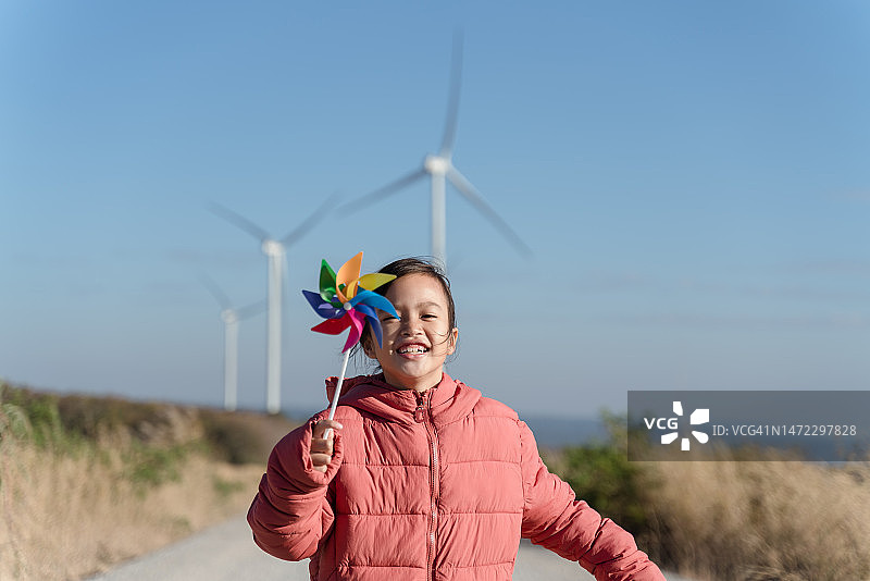 可爱的亚洲儿童女孩正在运行和玩风力发电机玩具与乐趣在风力发电机领域图片素材