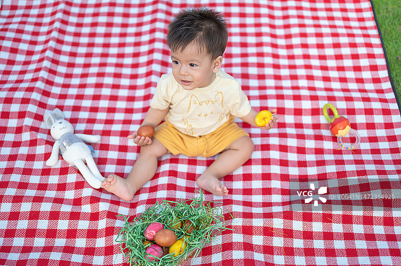 可爱的幼儿在户外野餐毯上放着一篮子复活节彩蛋图片素材
