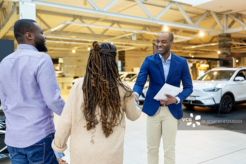 汽车销售员握手欢迎一对夫妇图片素材