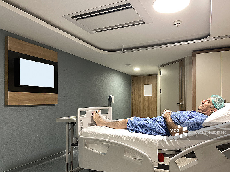 病人在病房看电视。病人准备做手术。在医院病房里，一个成熟的男人躺在病床上准备做手术，他看着电视屏幕(屏幕上有剪辑路径)图片素材