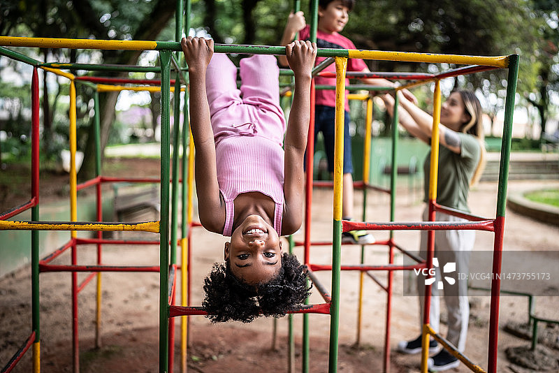 一个女孩在公园里的攀爬架上倒立着图片素材