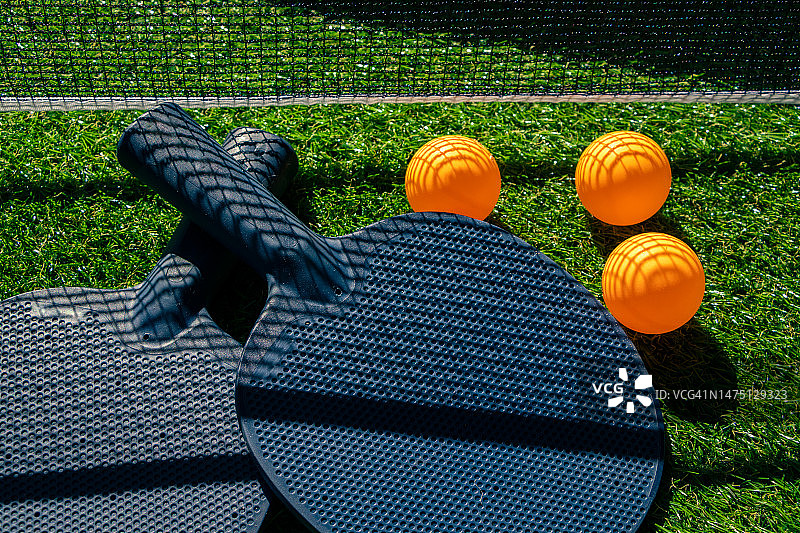 绿色草坪上的乒乓球球拍设备，远处有网图片素材